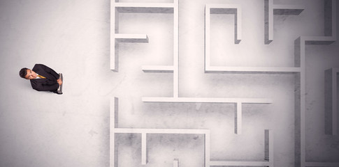 Confused businessman standing at a maze wall