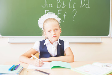 Schoolgirl sitting at desk, school classroom, and reading book