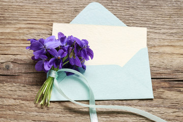 Bouquet of violets (viola odorata) and vintage envelope on wood