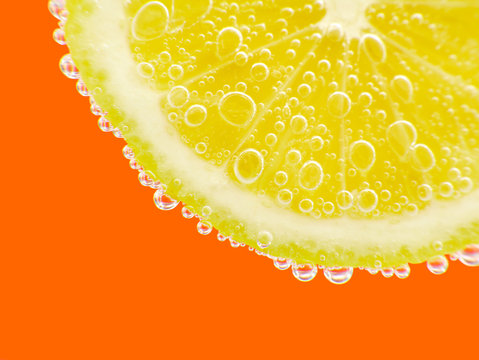 Close-up lemon in sparkling water orange background
