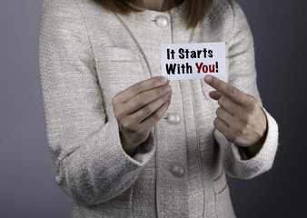 It Starts With You! Businesswoman holding a card with a message