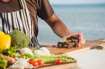 Sushi master cooking vegeterian roll on wooden board outdoor. Blurred foreground