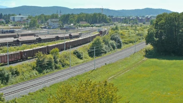 Aerial pan dolly shot of full loaded freight train departure.
