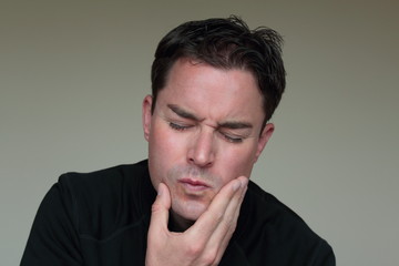 Man with toothache holding hand on face in pain