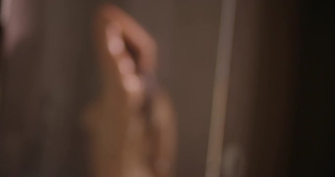 Defocused woman in shower behind the glass