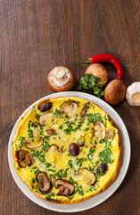 omelet with mushrooms in a plate on wooden table