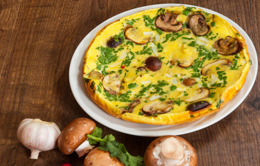 omelet with mushrooms in a plate on wooden table