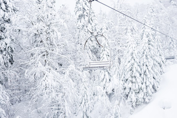 Old cable lift with no passengers going across coniferous forest in 'Kolasin 1450' mountain ski resort near the town of Kolasin, Montenegro after a heavy snowfall 