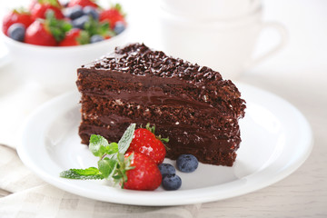 Chocolate cake with chocolate cream and fresh berries on plate, on light background