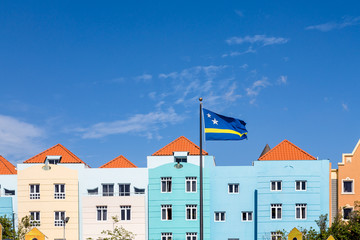 Curacao Flag by Blue Buildings under Blue Skies - obrazy, fototapety, plakaty