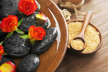 Spa wooden bowl with water, flowers and stones closeup