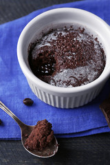 Chocolate fondant cake in cup on wooden table closeup