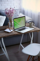 Modern interior. Comfortable workplace. Wooden table with beautiful bouquet of flowers and laptop on it.