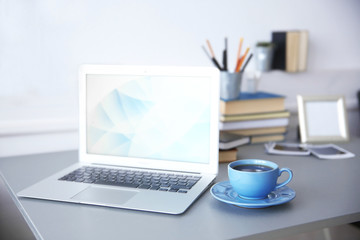 Fototapeta premium Modern interior. Comfortable workplace. Table with laptop and cup of coffee on it, close up