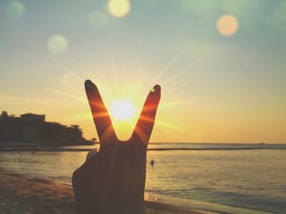 sun between fingers on beach