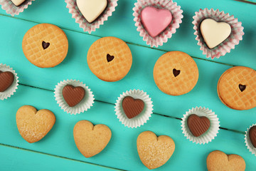 Valentine's Day concept. Composition of delicious chocolate candies and tasty cookies on turquoise wooden background