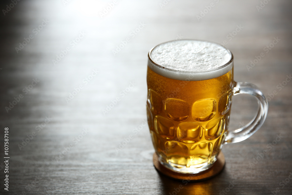 Wall mural glass mug of light beer on wooden table