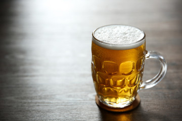 Glass mug of light beer on wooden table