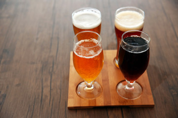 Glasses with different sorts of craft beer on wooden tray