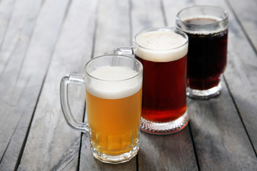 Glass mugs with different sorts of craft beer on wooden table