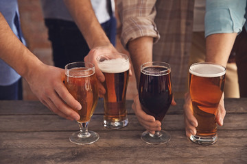 Male group holding glasses of dark and light beer at the table