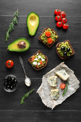 Avocado sandwiches with vegetables on dark wooden background