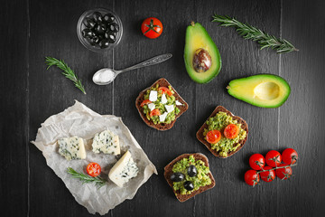 Avocado sandwiches with vegetables on dark wooden background