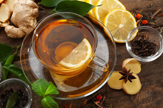 Cup of tea with ginger and cinnamon on wooden background