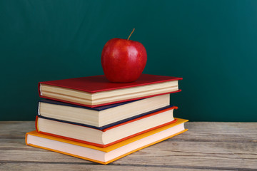 Few books with red apple on table
