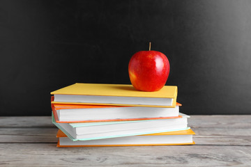 Few books with red apple on table