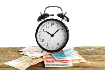 Alarm clock and money on wooden table.