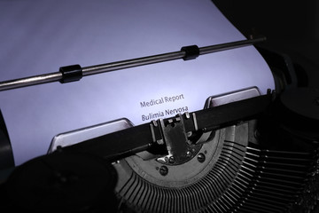 Old typewriter and inserted white sheet of paper with medical report on bulimia