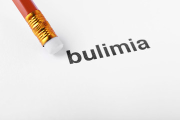 Bulimia word with pencil eraser on white paper background