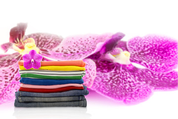 Pile of colorful clothes  on purple orchid flower background.