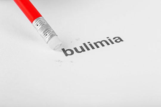 Bulimia word with pencil eraser on white paper background
