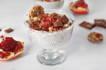 Chia seeds pudding with pomegranate grains and chocolate chips in glass saucer on white background