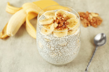 Chia seeds pudding with banana and hazelnut on grey textured background