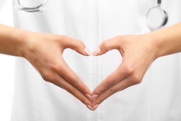 Young female doctor making heart with hand, close up
