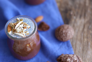 Chocolate chia seed pudding with crushed almonds on wooden table