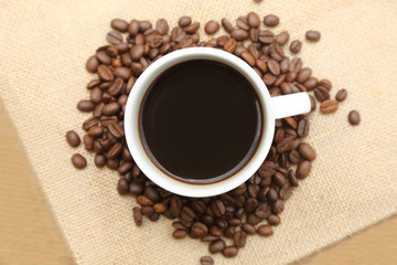 cup of coffee with roasted coffee on burlap sack