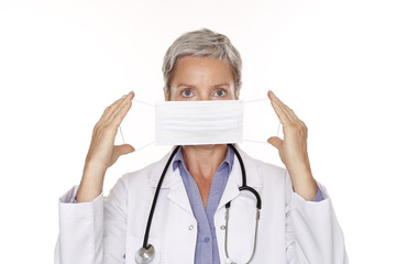Ärztin mit grauen Haaren hält sich Mundschutz vor das Gesicht