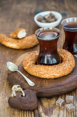 Turkish traditional black tea in a glass and turkish bagel simit on rustic  board over wooden background