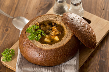 Fresh pea soup in bread bowl on a wooden desck