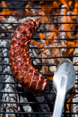 Grilling sausage on barbecue grill.