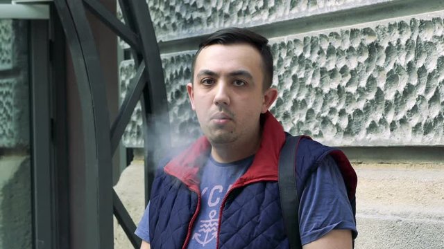 Man looking on camera and smoking cigarette outdoor Slowly