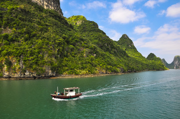 Fototapeta na wymiar Small motor boat races among the islands of Halong Bay