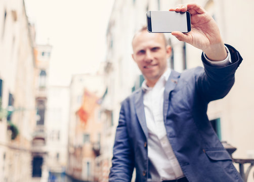 Man with modern smartphone take a selfie photo on Venice street