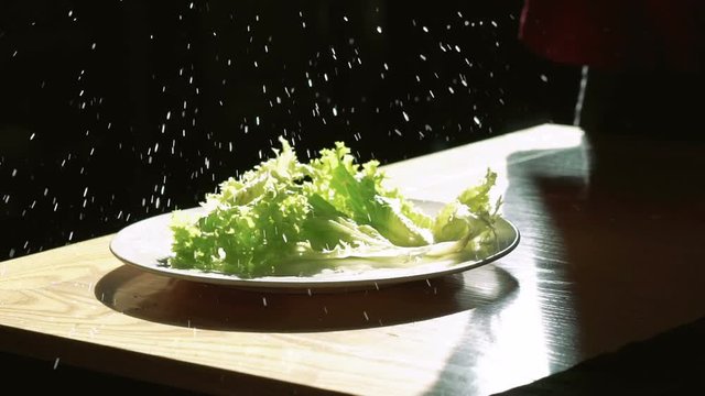 Lettuce falling and splashing with water drops on black background. Slowly