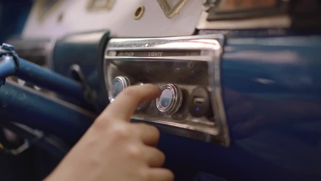 Preteen boy learning to drive a car. The kid is sitting in a vintage auto from the 50s, playing with buttons and controls on the dashboard