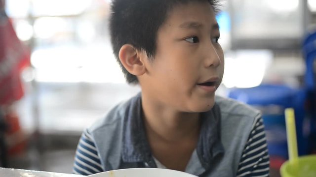Asian boy eating rice at local shop